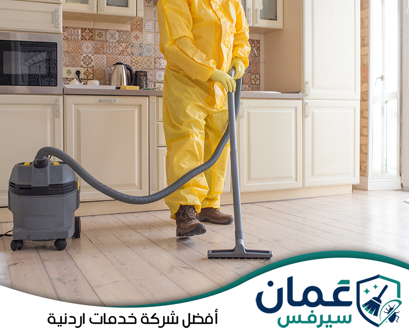 اطلب تنظيفًا عميقًا للشقة عبر 0798779667. عامل يستخدم مكنسة شفط لتنظيف أرضيات الشقة وإزالة الأتربة من المساحات المحيطة بالمطبخ والأثاث.