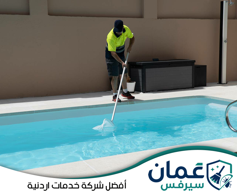 احجز خدمة تنظيف وصيانة المسبح على 0798779667. عامل ينفذ تنظيفًا دوريًا للمسبح باستخدام شبكة طويلة للوصول إلى الشوائب داخل المياه.