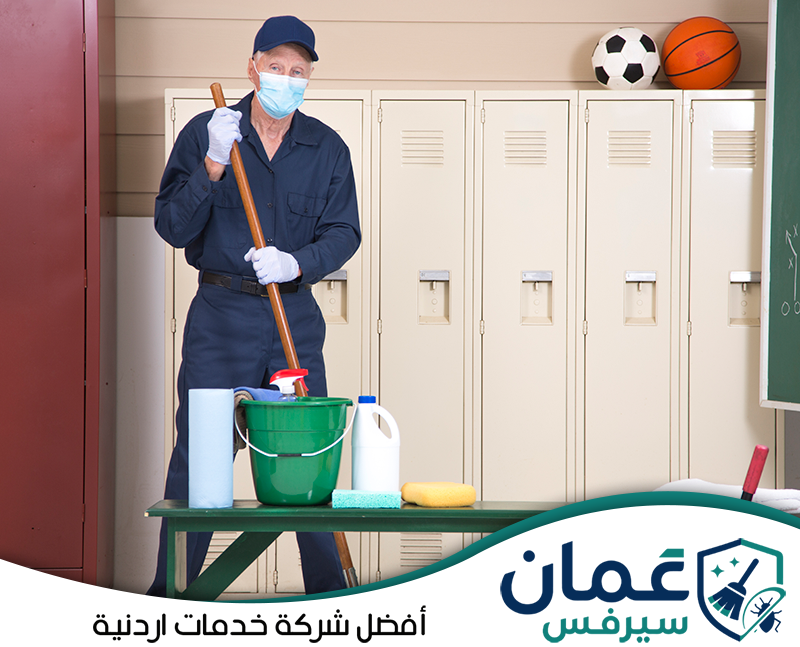احجز تنظيف مرافق المدرسة على 0798779667. عامل مجهز بأدوات التنظيف داخل أحد مرافق المدرسة وخزائن الطلاب.