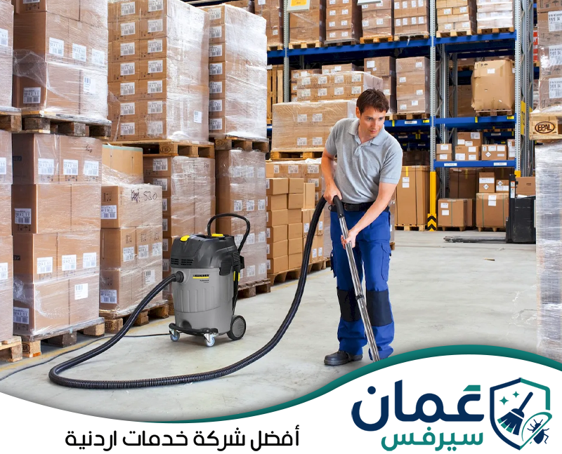 تواصل مع عمان سيرفس لتنظيف المستودعات والمخازن في الأردن. عامل يستخدم مكنسة شفط صناعية لتنظيف أرضيات المستودع وإزالة الغبار من المساحات المحيطة بالبضائع.