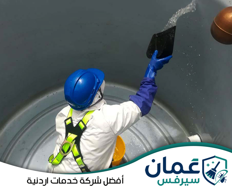 احجز تنظيف وتعقيم خزان المياه مع عمان سيرفس0798779667. عامل مزود بمعدات حماية ينظف الجدران الداخلية لخزان مياه باستخدام أدوات مخصصة.